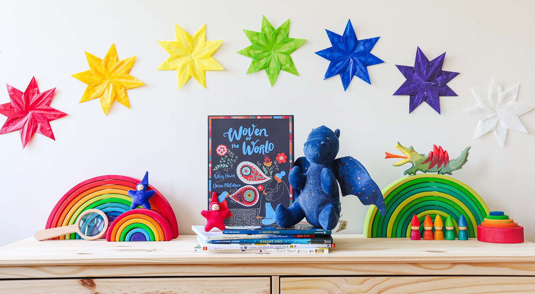 A collection of books on a pine dresser with wooden rainbows.