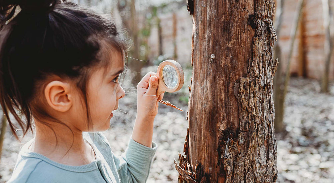 Top 10 Nature Toys for Easter Baskets hero image with a boy holding a wooden magnifying glass.