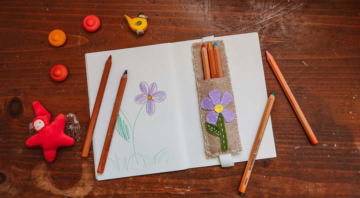 A handmade elastic felt pencil pouch on a wooden table.