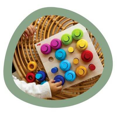 A child picks up a peg from the wooden peg board game.