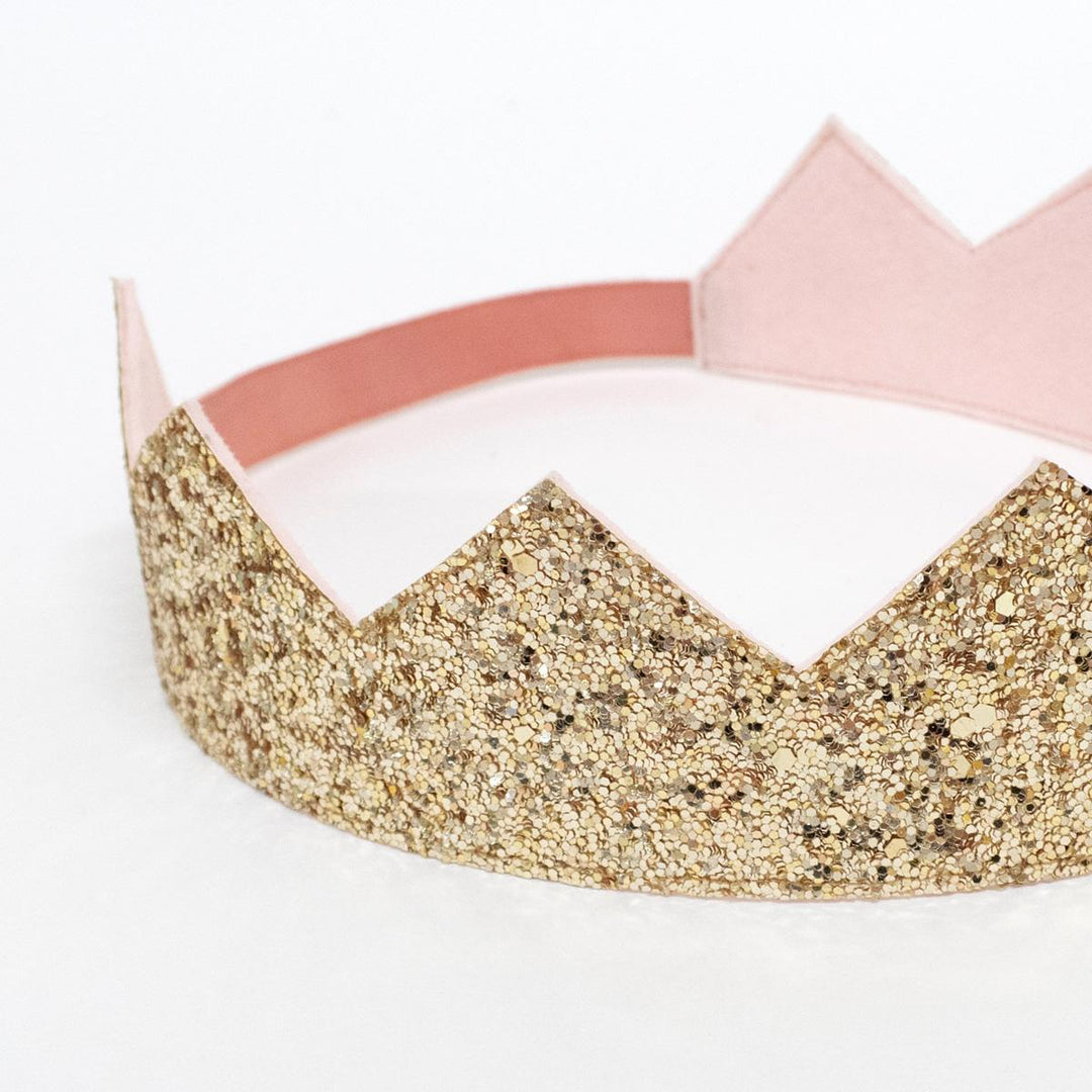 A close up of the gold glitter crown and the pink elastic band from the Meri Meri Rainbow Princess costume set. 
