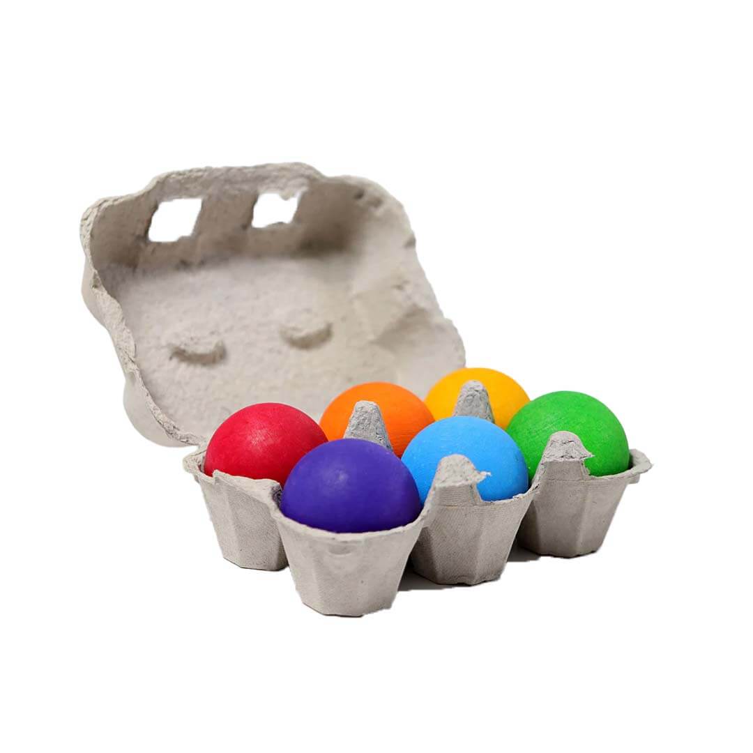 Colorful balls in an open cardboard egg carton on a white background.
