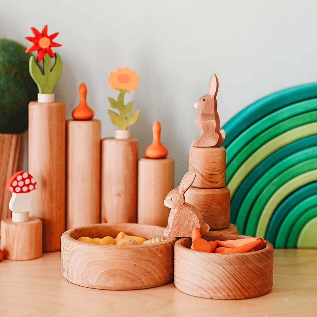 Wooden toys including rabbits, flowers, and a rainbow on a light surface.