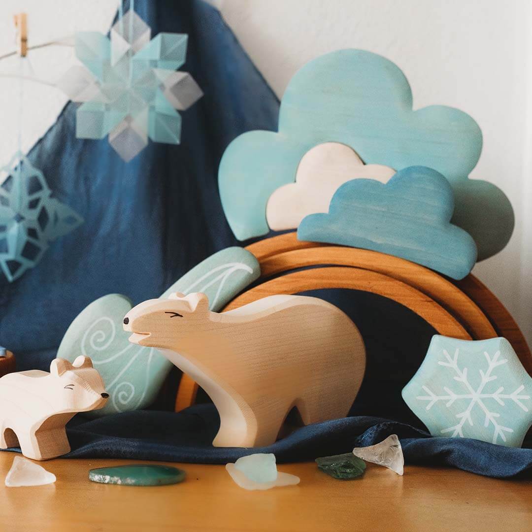 Wooden bear and toys with a decorative cloud and snowflake on a wooden surface.