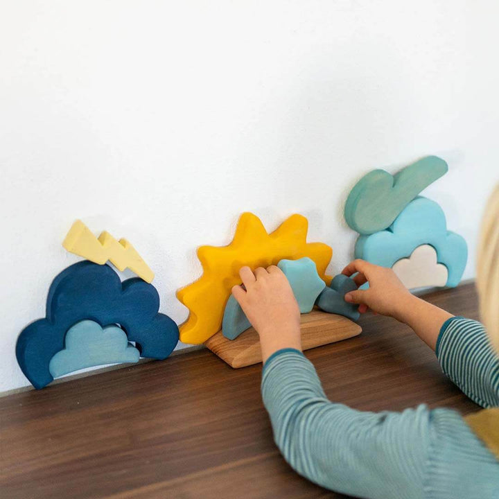 Children playing with colorful wooden toys  that represent the weather on a wooden surface.