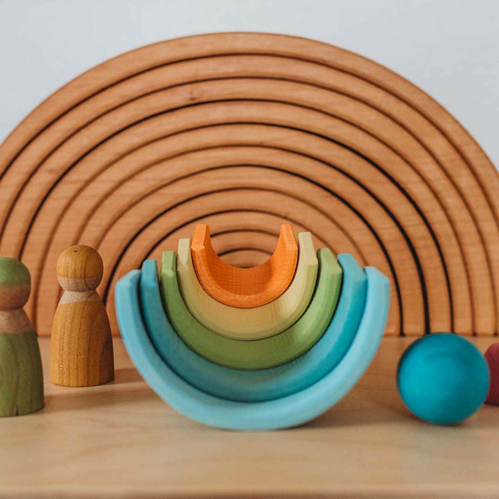 Set of colorful wooden rings and blocks on a wooden surface with a wooden structure in the background.