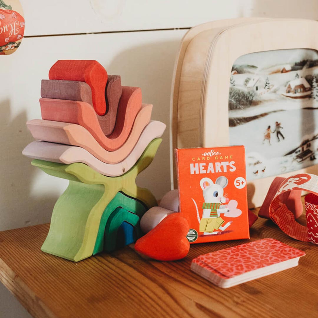 Colorful wooden stacking toy and card game on a wooden surface with a blurred background.