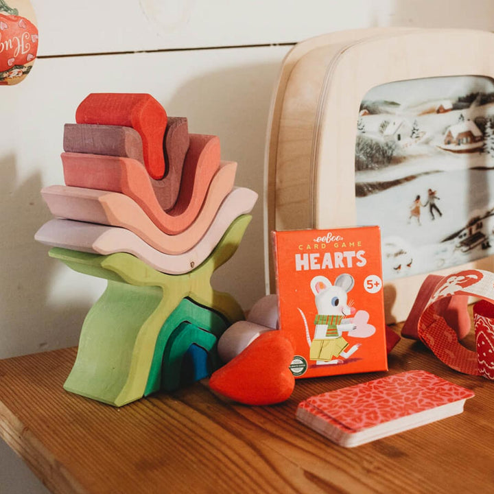 Colorful wooden stacking toy and card game on a wooden surface with a blurred background.