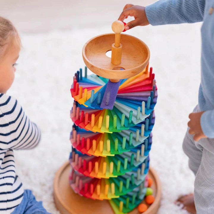 Colorful tower toy with children playing around it on a light background.