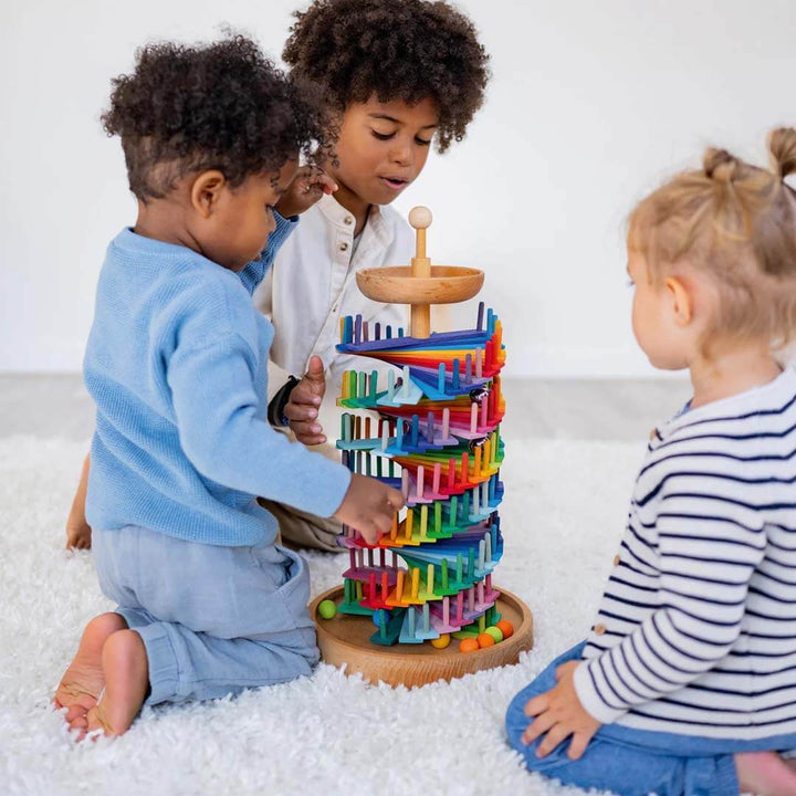 Children playing with a colorful wooden toy on a white floor.