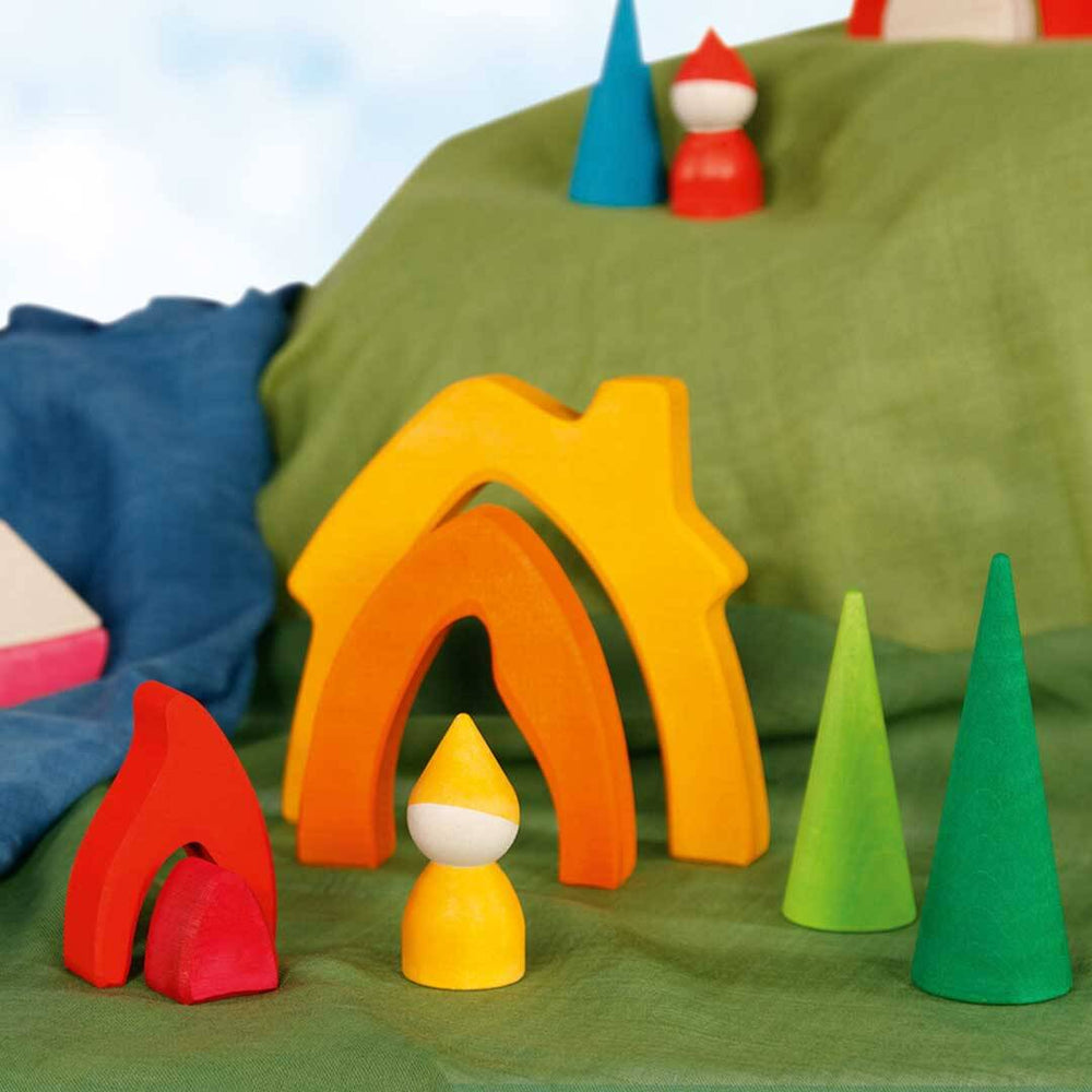 A set of colorful wooden toy blocks arranged on a green fabric surface, including arch-shaped pieces in yellow, orange, and red, cone-shaped pieces in blue and green, and small peg-like figures with red, yellow, and white tops - Bella Luna Toys