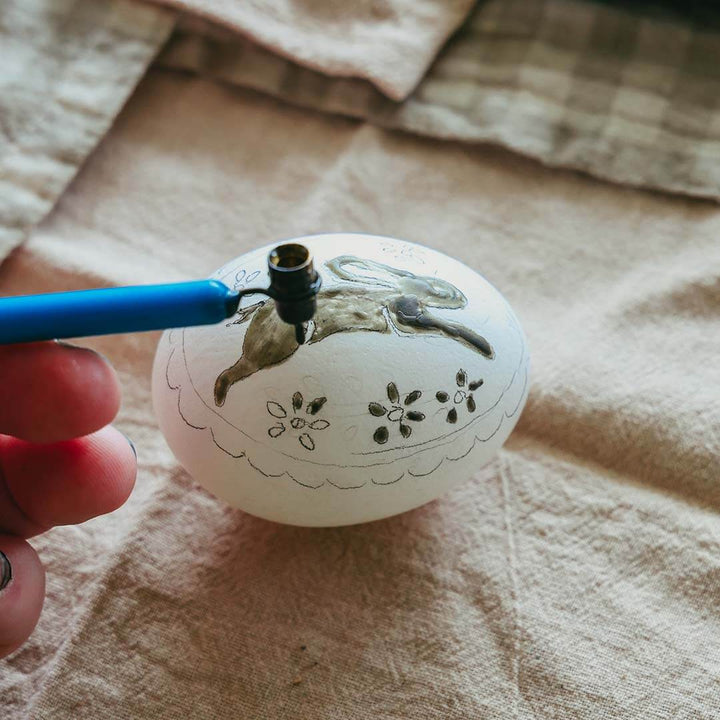 A Kid's Guide to Decorating Ukrainian Easter Eggs Kit being used on an egg with a bunny pattern.
