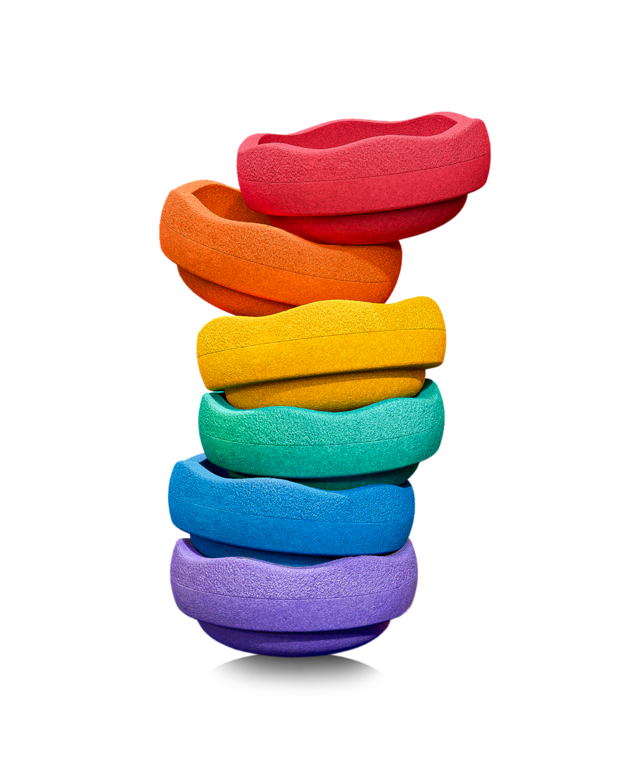 Stack of seven colorful Stapelstein Original Rainbow stones arranged in a vertical tower, showcasing red, orange, yellow, green, turquoise, blue, and violet stones on a transparent background.