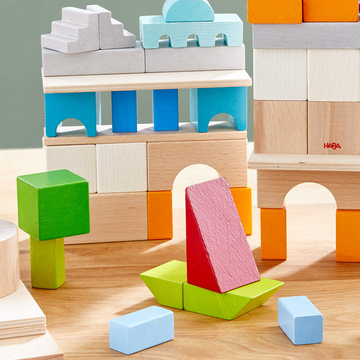 A colorful HABA wooden block structure featuring various shapes, including a boat, on a wooden surface.