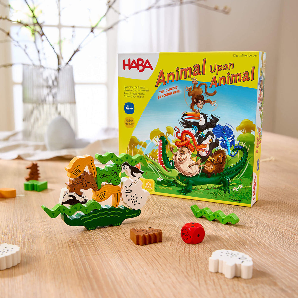 Animal Upon Animal wooden animal stacking game with a colorful game box in the background on a wooden table.