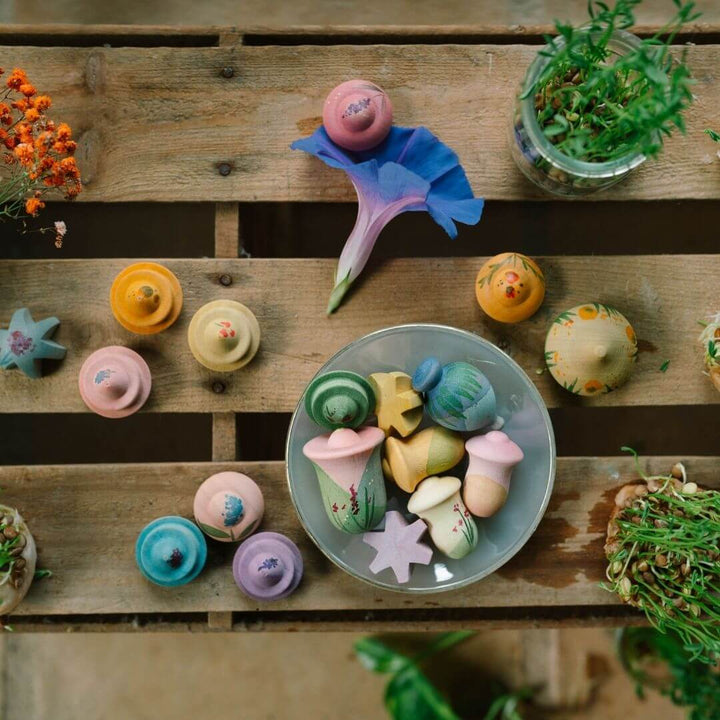 Grapat - Grapat Flower Meadow set with 18 hand-painted wooden flower pieces in soft pastel colors, displayed on an outdoor table with a bowl and plants - Bella Luna Toys