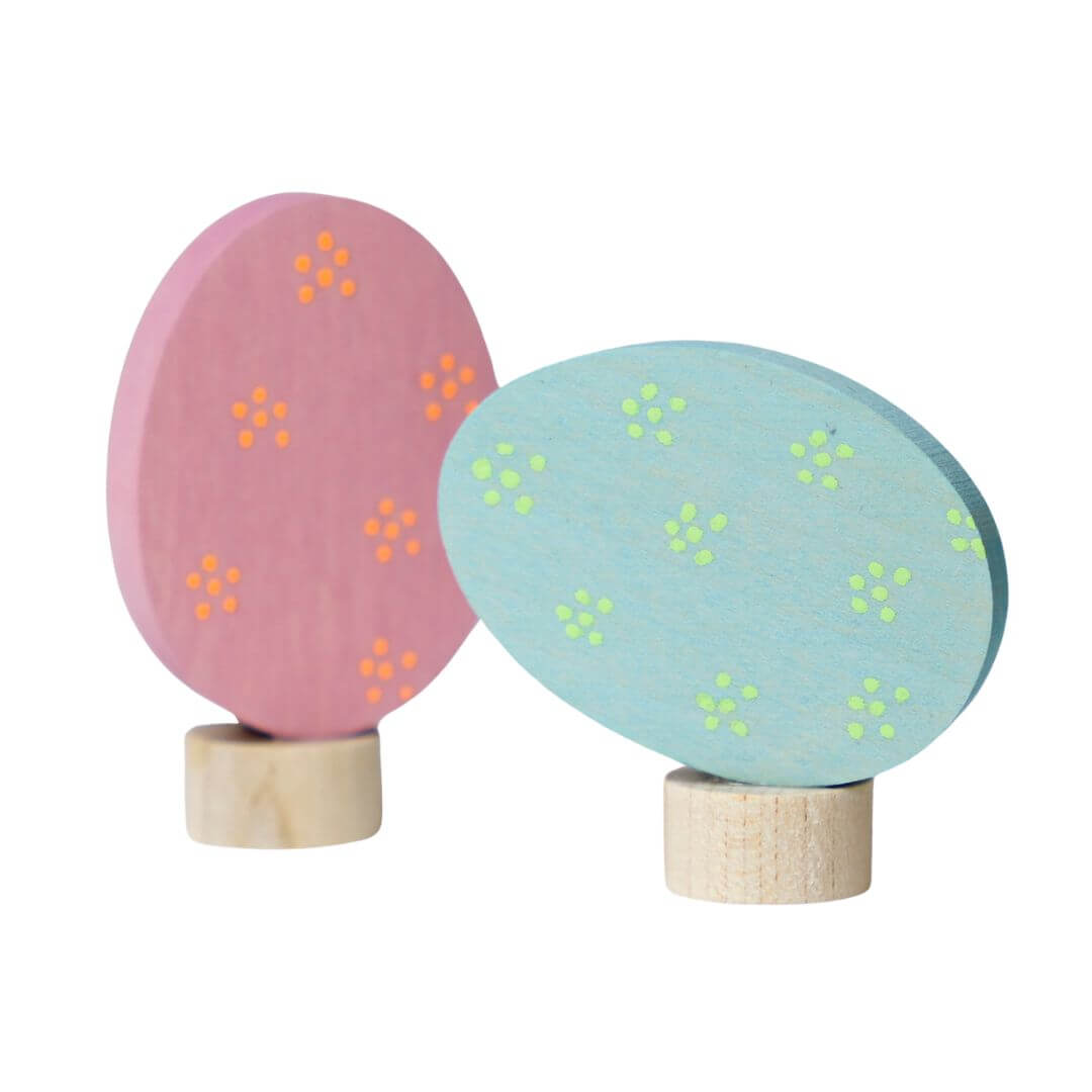 Grimm’s Wooden Easter Eggs in the Floral Colorway, showing thepink with neon orange dotted egg and the pale blue with neon yellow colors of the two eggs. 