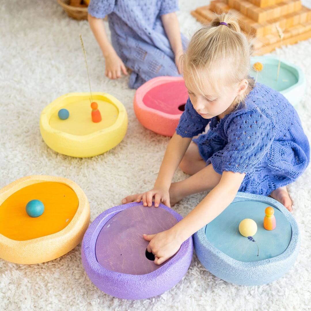 A child is placing a purple rolling disc into a purple Stapelstein stepping stone.