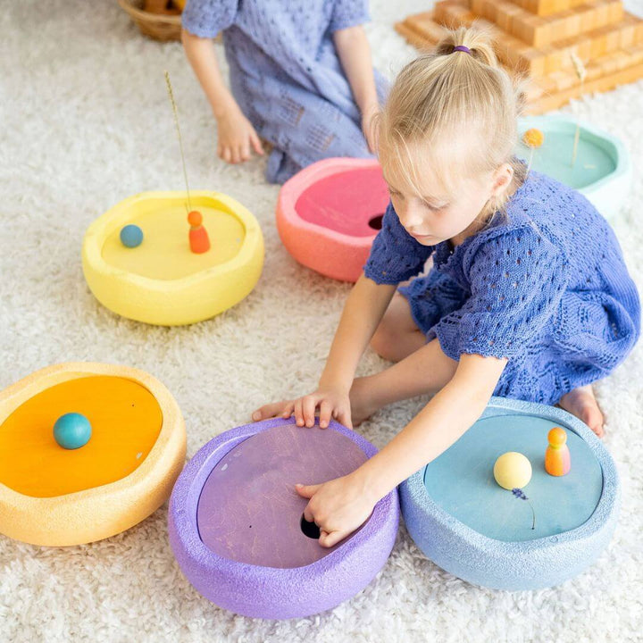 A child is placing a purple rolling disc into a purple Stapelstein stepping stone.