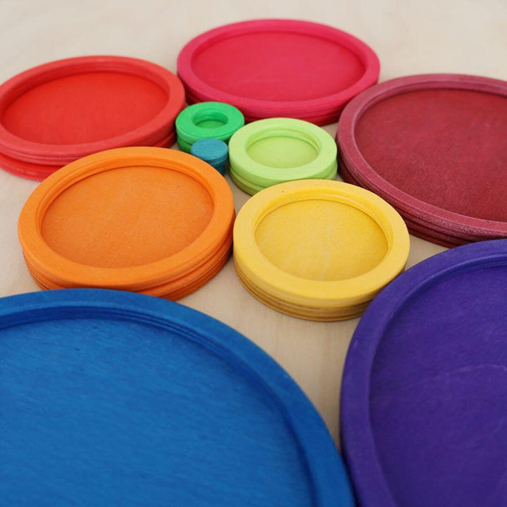 Close-up of Grimm's colorful wooden circles and rings stacked and nested on a table, showcasing rainbow hues and fine craftsmanship.
