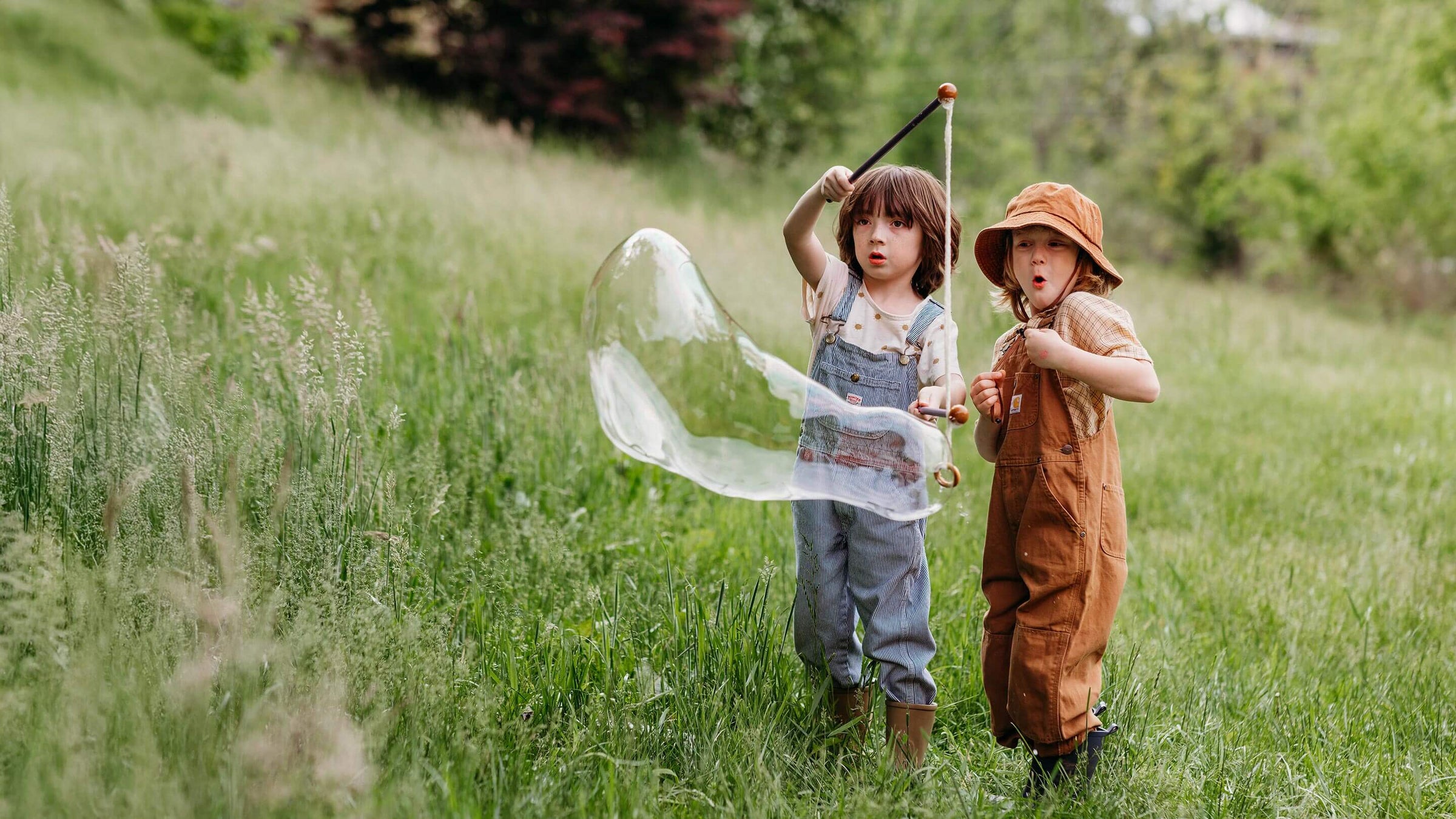 Two children playing with bubbles in a grassy field