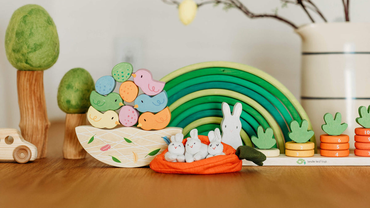 Colorful toy set with a rainbow, animals, and trees on a wooden surface.