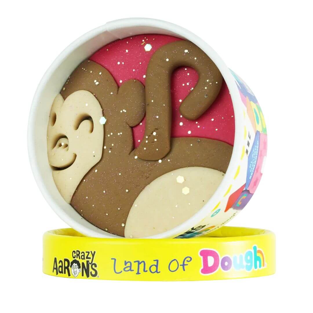 Monkey-shaped Land of Dough play dough cup with colorful compostable glitter in a round yellow container, featuring eco-friendly, sensory play packaging.