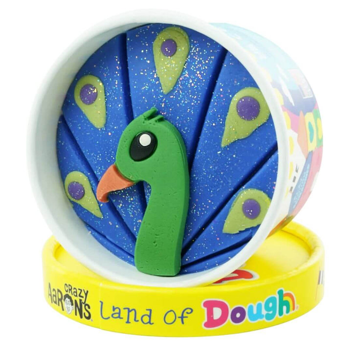 Peacock-shaped Land of Dough play dough cup with colorful compostable glitter in a round yellow container, featuring eco-friendly, sensory play packaging.