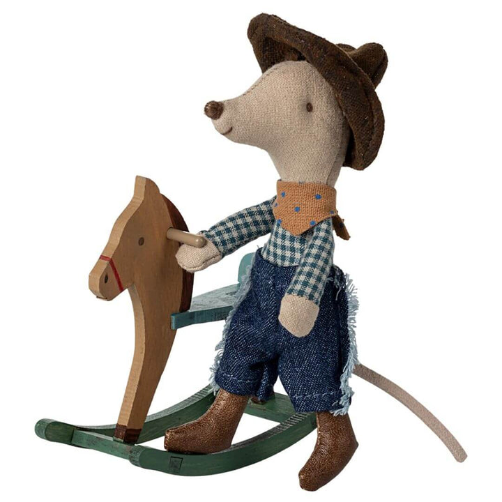 Maileg Little Brother Cowboy Mouse wearing jeans, a plaid shirt, scarf, and cowboy hat, standing next to a wooden rocking horse with a tail.