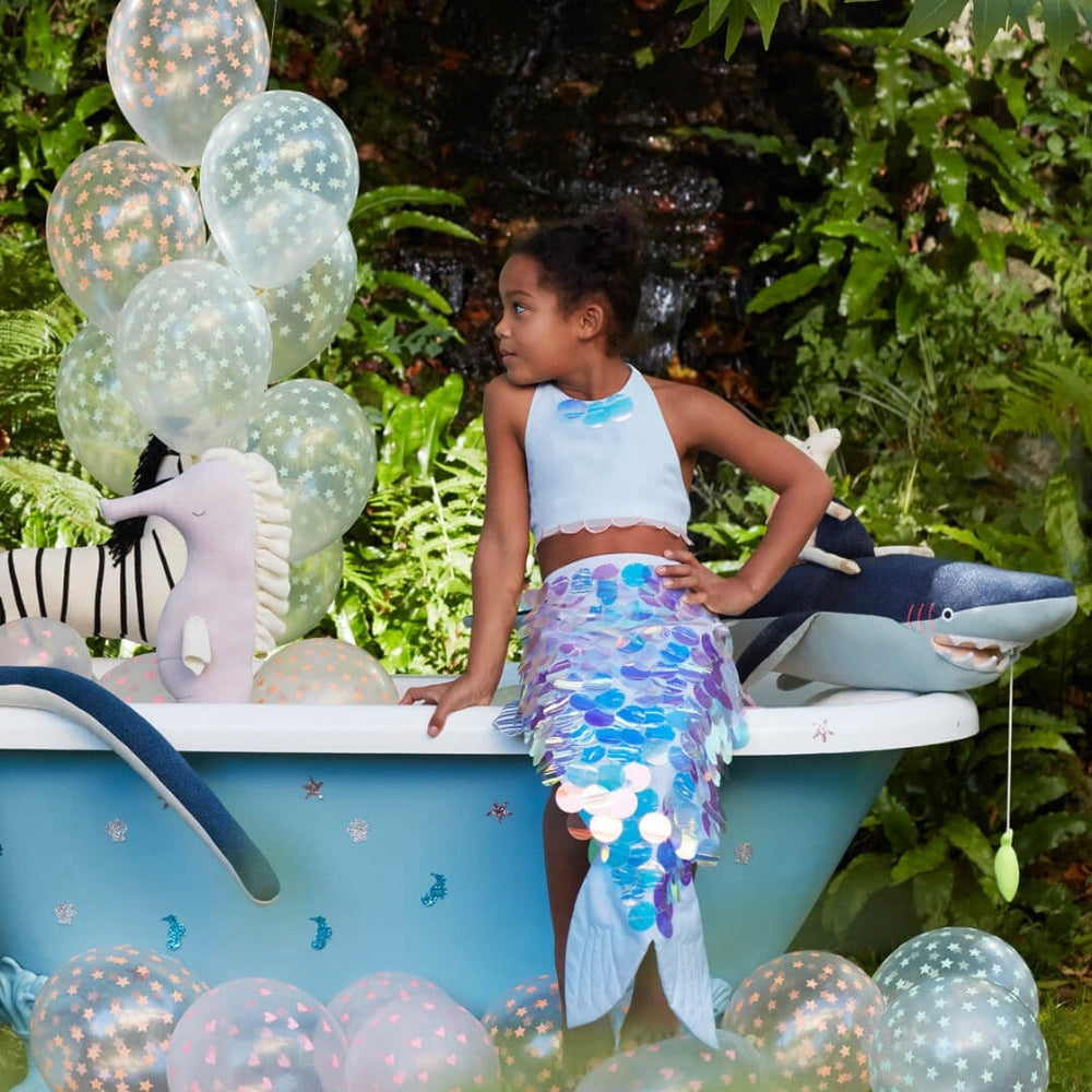 A girl sitting on the edge of a tub wearing the Meri Meri mermaid costume.
