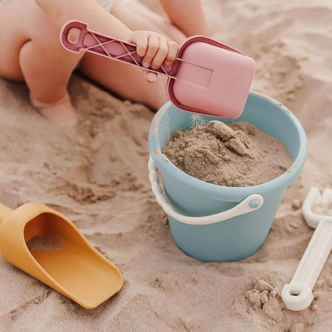 A child putting sand in a blue bucket from the Miniland - ECO Large Sand Toys 4 Piece Set - Bella Luna Toys