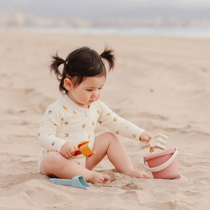 A child sitting in the sand playing with the Miniland ECO Small Sand Toys 4 Piece Set - Bella Luna Toys