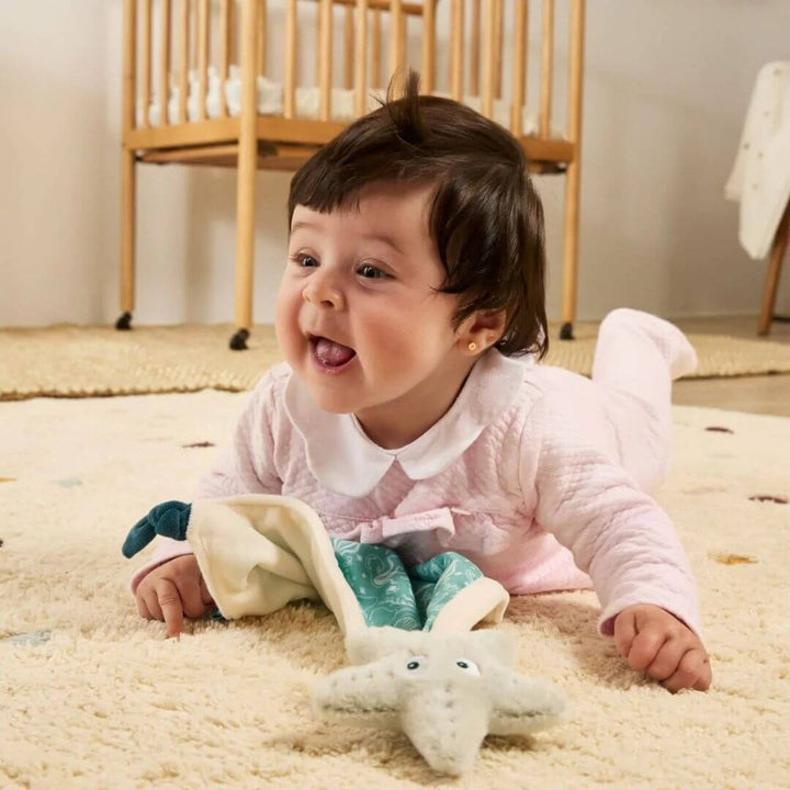 Miniland - Child playing with the starfish from the Ocean-Themed Baby Gift Set on a cozy rug in a nursery - Bella Luna Toys
