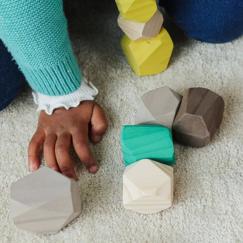 Miniland - Child stacking wooden stones in soft natural tones, exploring balance and tactile play on a cozy rug - Bella Luna Toys