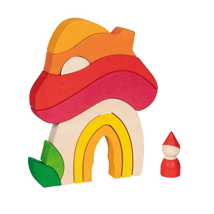 A wooden toy house puzzle with a red mushroom-shaped roof, yellow and orange arched doorway, green leaf detail, and two loose orange and yellow pieces on a white background.