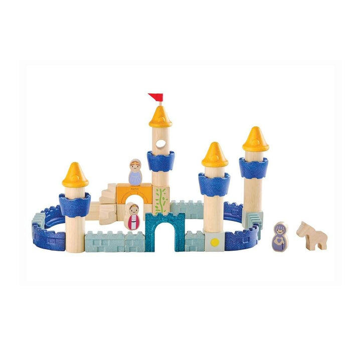 PlanToys wooden castle block set arranged as a fortress with blue and yellow towers, arches, walls, and small wooden figures including a king, queen, knight, and horse. Bella Luna Toys