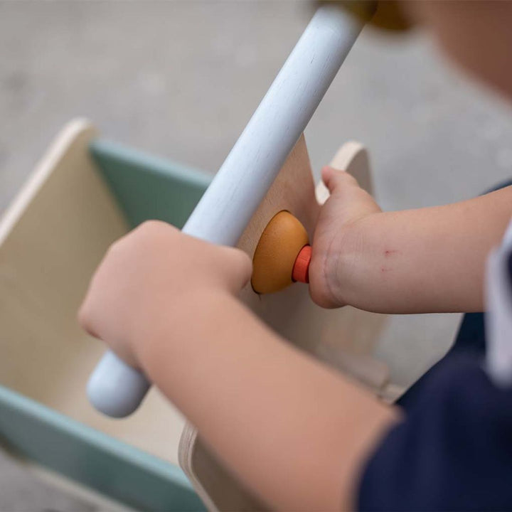 A close up of a child pushing the horn that makes a beep beep sound on PlanToys Delivery Bike.