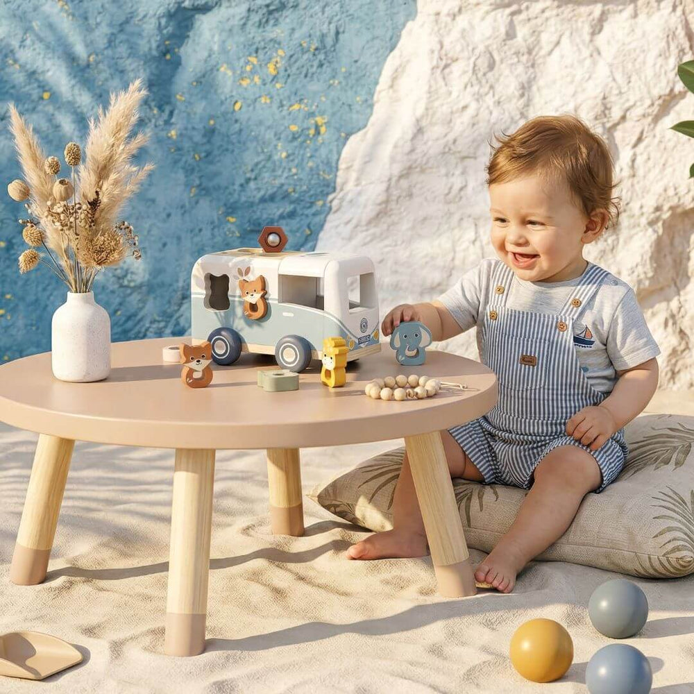 A child playing with animal themed shape sorting van at a small table.