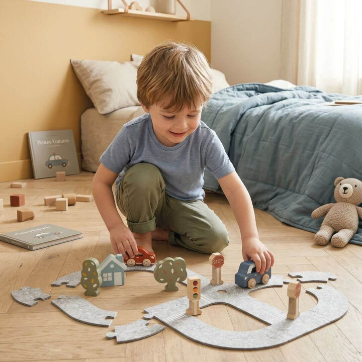 A child drives a wooden car on the Speedy Monkey felt roadways set.