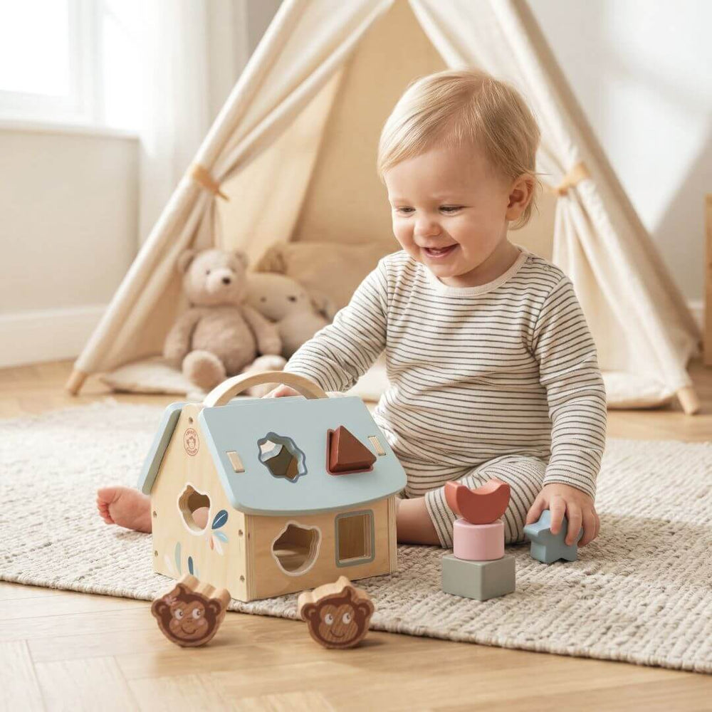A child placing colorful blocks into a shape sorter. Speedy Monkey - Wooden Toy House Shape Sorter - Bella Luna Toys