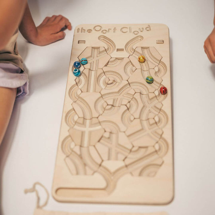 Children playing with the wooden marble maze game board with rearrangeable hexagon tiles and colorful marbles, set on a white floor surface - Bella Luna Toys