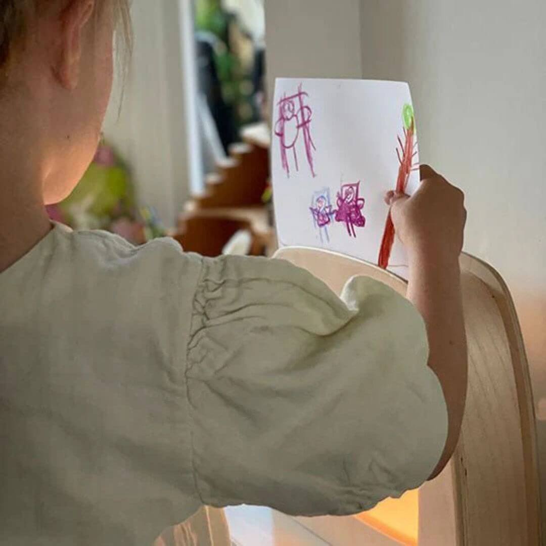 A child places their own drawing on the diy transparency pages into their Toverlux lamp.